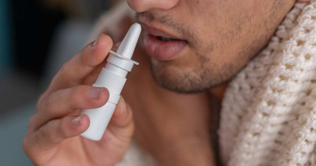 Hombre que usa spray nasal como tratamiento para las alergias.