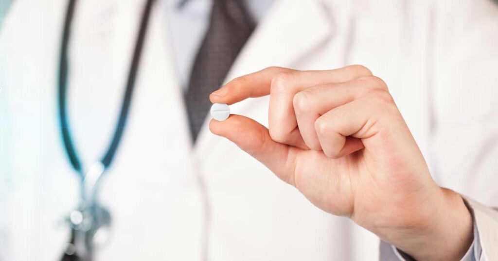 Médico sosteniendo una pastilla para la alergia.